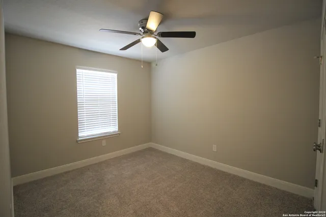 an empty room with a window and a fan