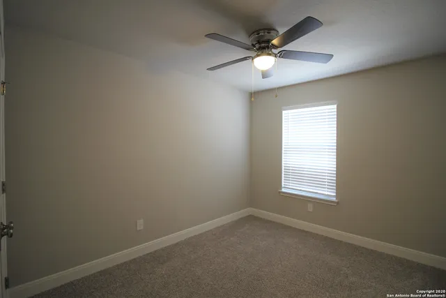 an empty room with a window and a fan