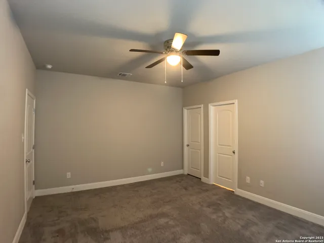 an empty room with closet and a chandelier fan