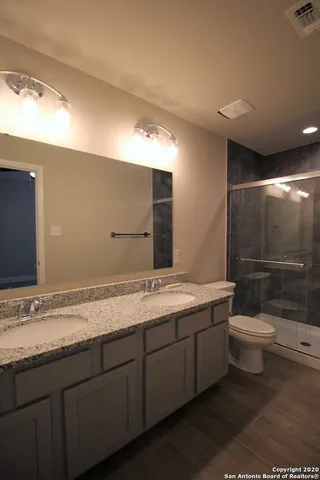 a bathroom with a granite countertop sink a toilet and a shower