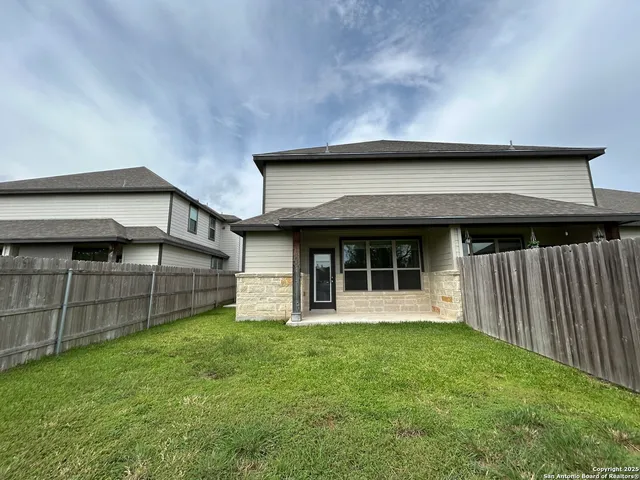 a view of a house with a yard and wooden fence