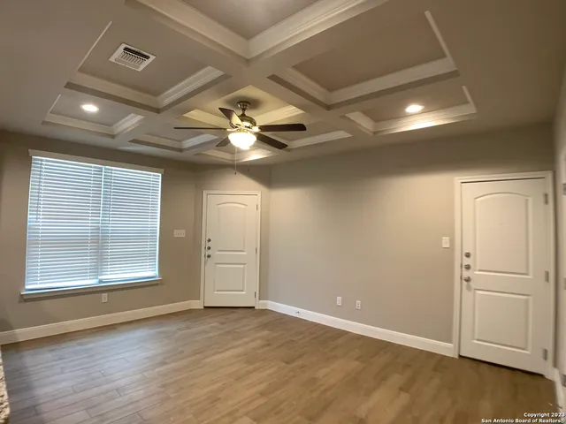 an empty room with wooden floor chandelier and windows