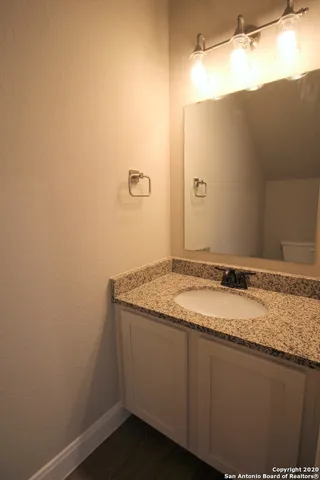a bathroom with a granite countertop sink and a mirror