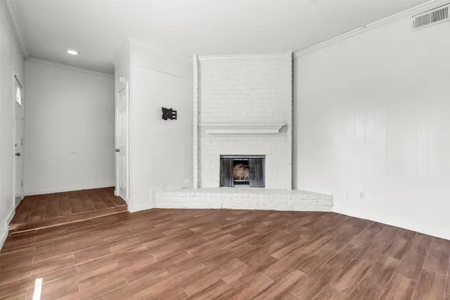 a view of empty room with wooden floor and fireplace