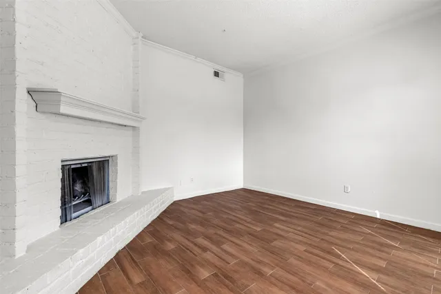 a view of empty room with wooden floor and fireplace