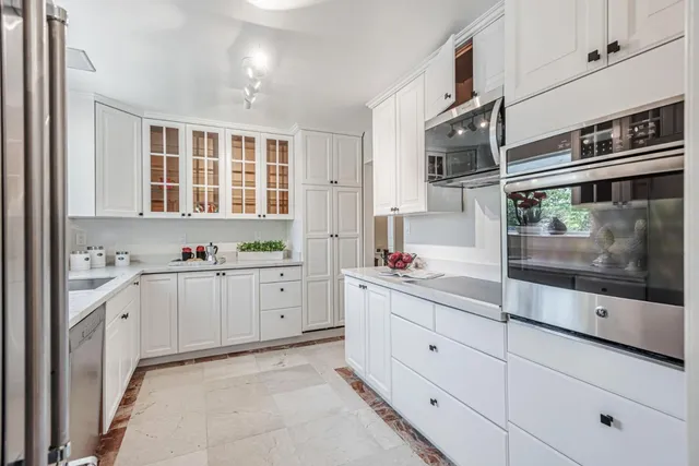 a large white kitchen with stainless steel appliances granite countertop a stove and a sink