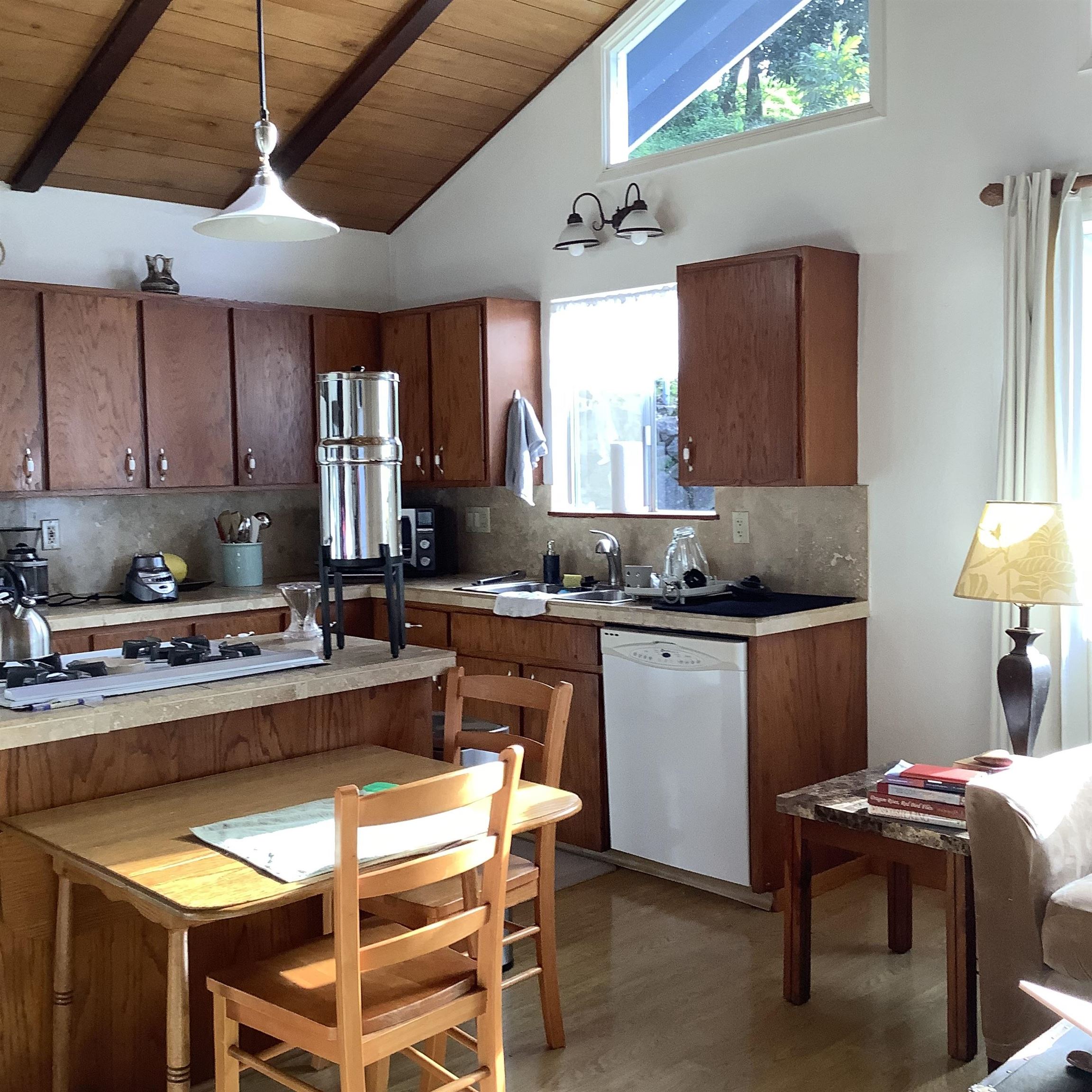 246 Koheo Road Kula, HI 96790 - Photo 9 of 24 a kitchen with a dining table chairs sink and white cabinets
