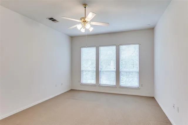 an empty room with a chandelier fan and windows