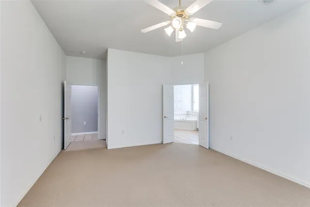 an empty room with a chandelier fan and windows