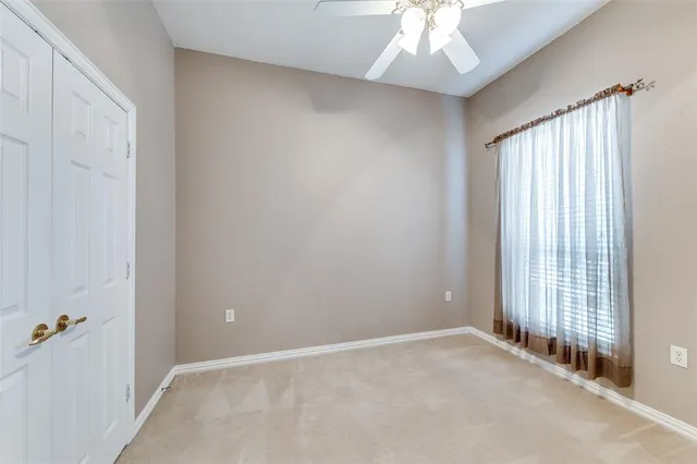 an empty room with chandelier fan and windows