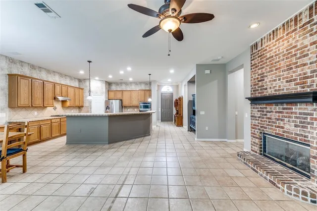 a large kitchen with stainless steel appliances kitchen island granite countertop a refrigerator a oven a sink and a black cabinets