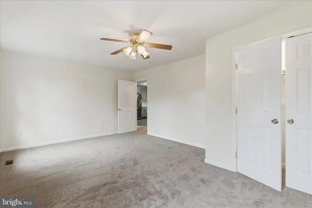 a view of an empty room and chandelier fan