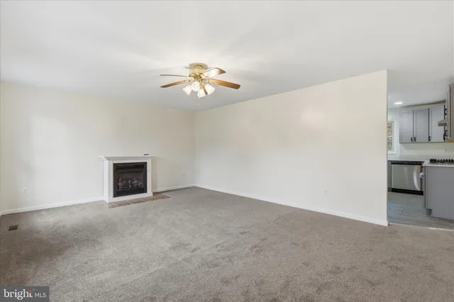 an empty room with a fireplace and a chandelier fan