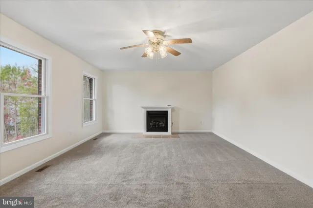 a view of an empty room with window and chandelier fan