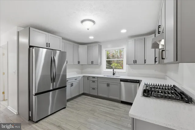 a kitchen with stainless steel appliances granite countertop a refrigerator stove sink and cabinets