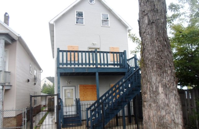 a view of a house with wooden deck and a large tree