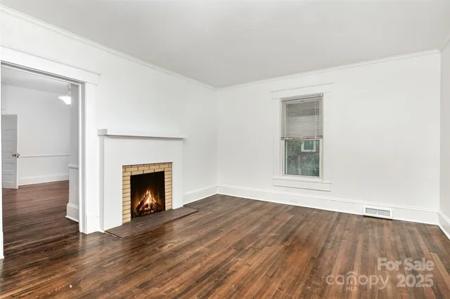 a view of empty room with wooden floor and fireplace