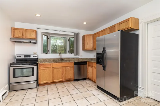 a kitchen with stainless steel appliances granite countertop a refrigerator and a sink