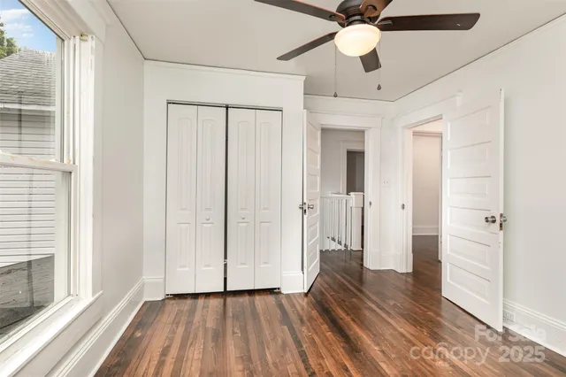 a view of a hallway with wooden floor and a ceiling fan