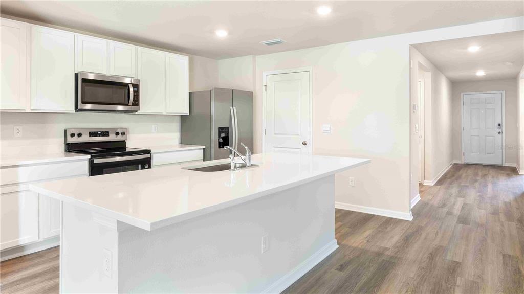 10931 Rabbit Grove Trail Palmetto, FL 34221 - Photo 4 of 30 a kitchen with stainless steel appliances a microwave a stove a sink and white cabinets