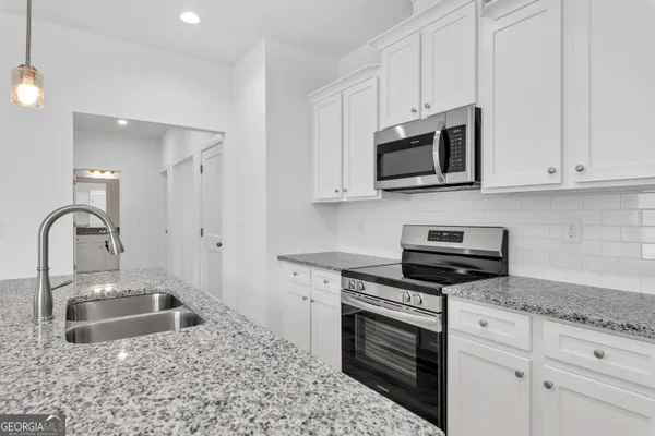 a kitchen with stainless steel appliances granite countertop a sink stove and microwave