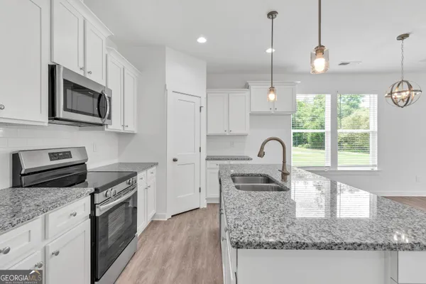 a kitchen with stainless steel appliances granite countertop a sink a stove a microwave a counter space and cabinets