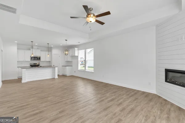 a view of kitchen with kitchen island wooden floors appliances and cabinets