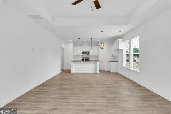 a view of an empty room with kitchen and a window