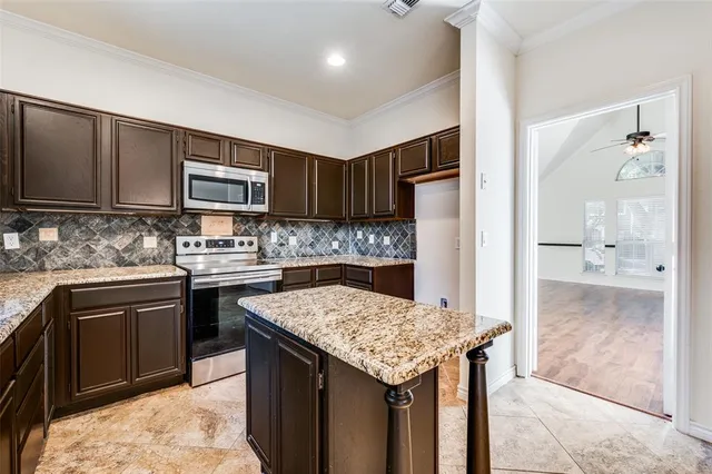 a kitchen with kitchen island granite countertop wooden cabinets and a refrigerator