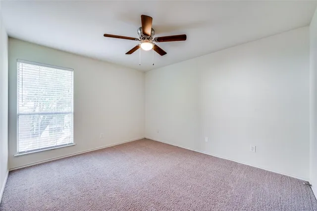 an empty room with a ceiling fan and window