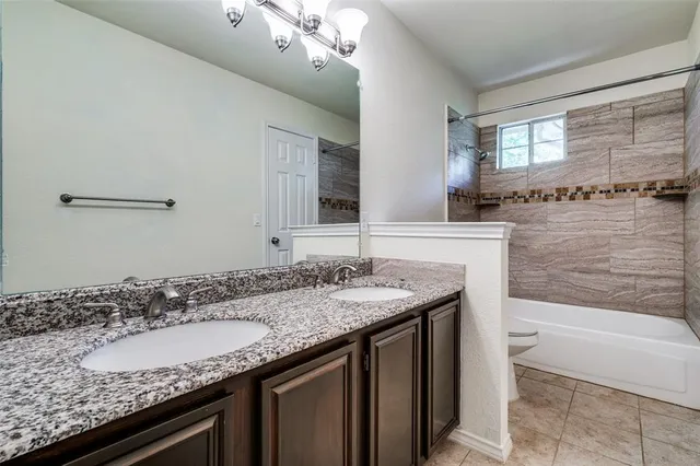 a bathroom with a granite countertop sink a toilet and bathtub