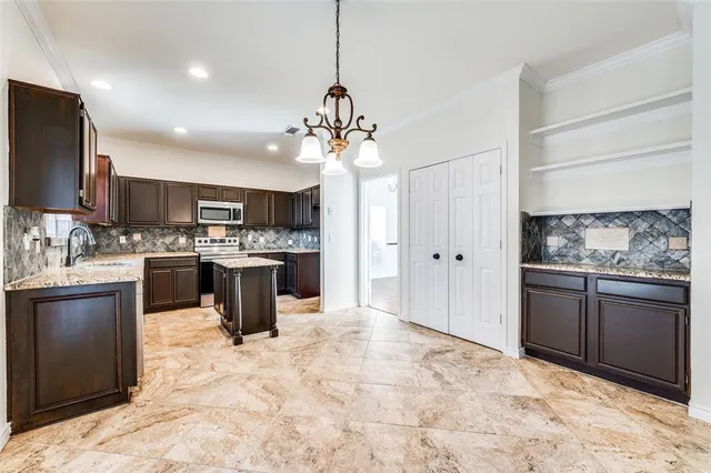 a kitchen with stainless steel appliances kitchen island granite countertop a sink stove and refrigerator