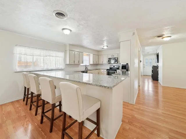 a kitchen with stainless steel appliances granite countertop a table chairs sink refrigerator and cabinets