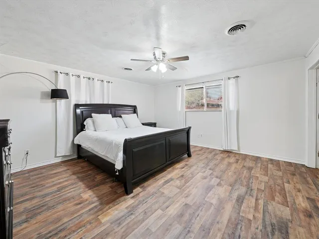 a bedroom with a bed and a ceiling fan with wooden floor