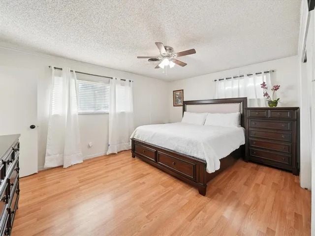 a spacious bedroom with a bed and wooden floor