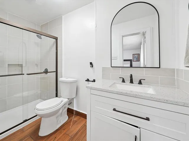 a bathroom with a granite countertop sink toilet a mirror and shower