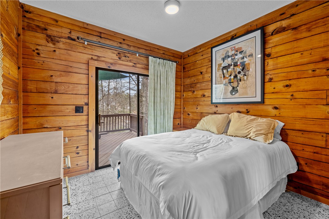 203 Little Lane Seneca, SC 29672 - Photo 22 of 48 This cozy bedroom features warm wood walls and a private balcony, perfect for serene mornings.
