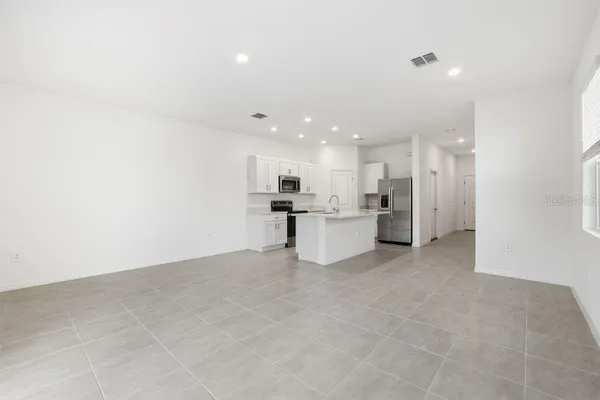 a view of a kitchen with refrigerator and white walls
