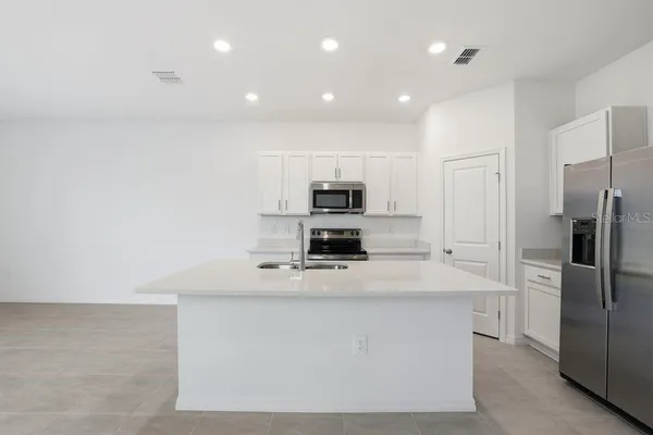 a large kitchen with stainless steel appliances a refrigerator and a stove top oven