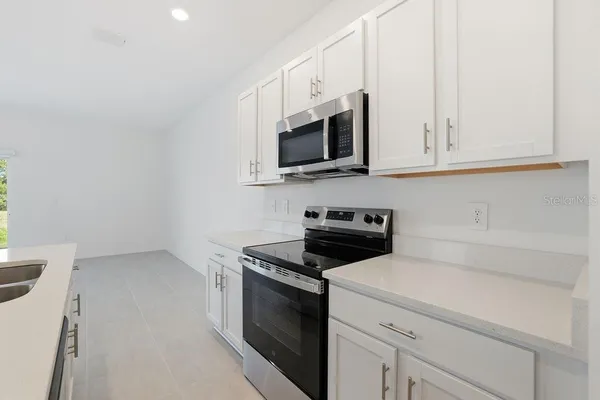 a kitchen with white cabinets and black appliances