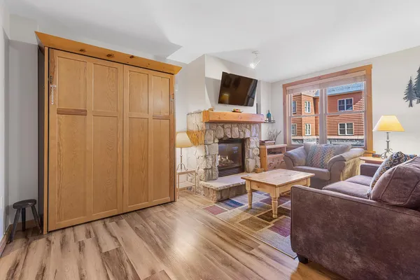 a spacious bedroom with a bed a couch and dresser with wooden floor