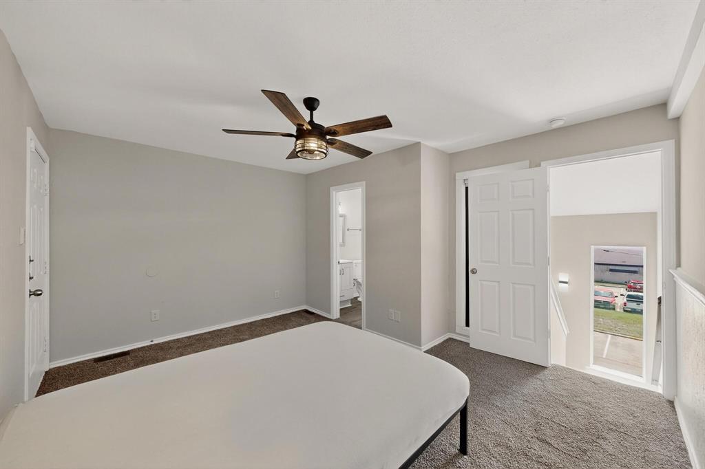 9809 Walnut Street, Unit E209 Dallas, TX 75243 - Photo 23 of 31 a bedroom with a bed and a chandelier