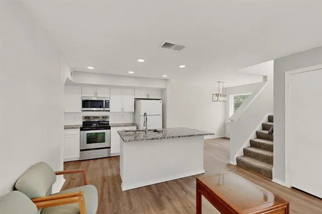 a kitchen with stainless steel appliances kitchen island granite countertop a refrigerator and a stove top oven