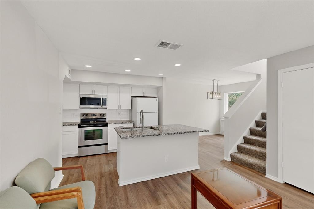 9809 Walnut Street, Unit E209 Dallas, TX 75243 - Photo 29 of 31 a kitchen with stainless steel appliances kitchen island granite countertop a refrigerator and a stove top oven