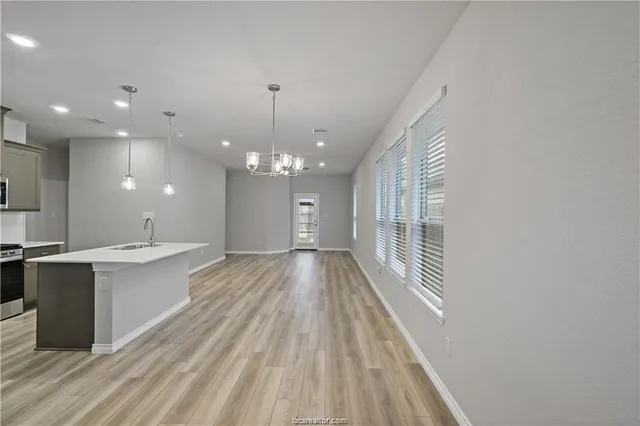 a view of a kitchen with kitchen island a sink wooden floor and a large window