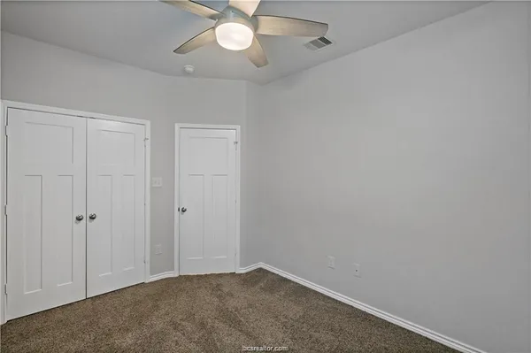 an empty room with a chandelier fan and closet area