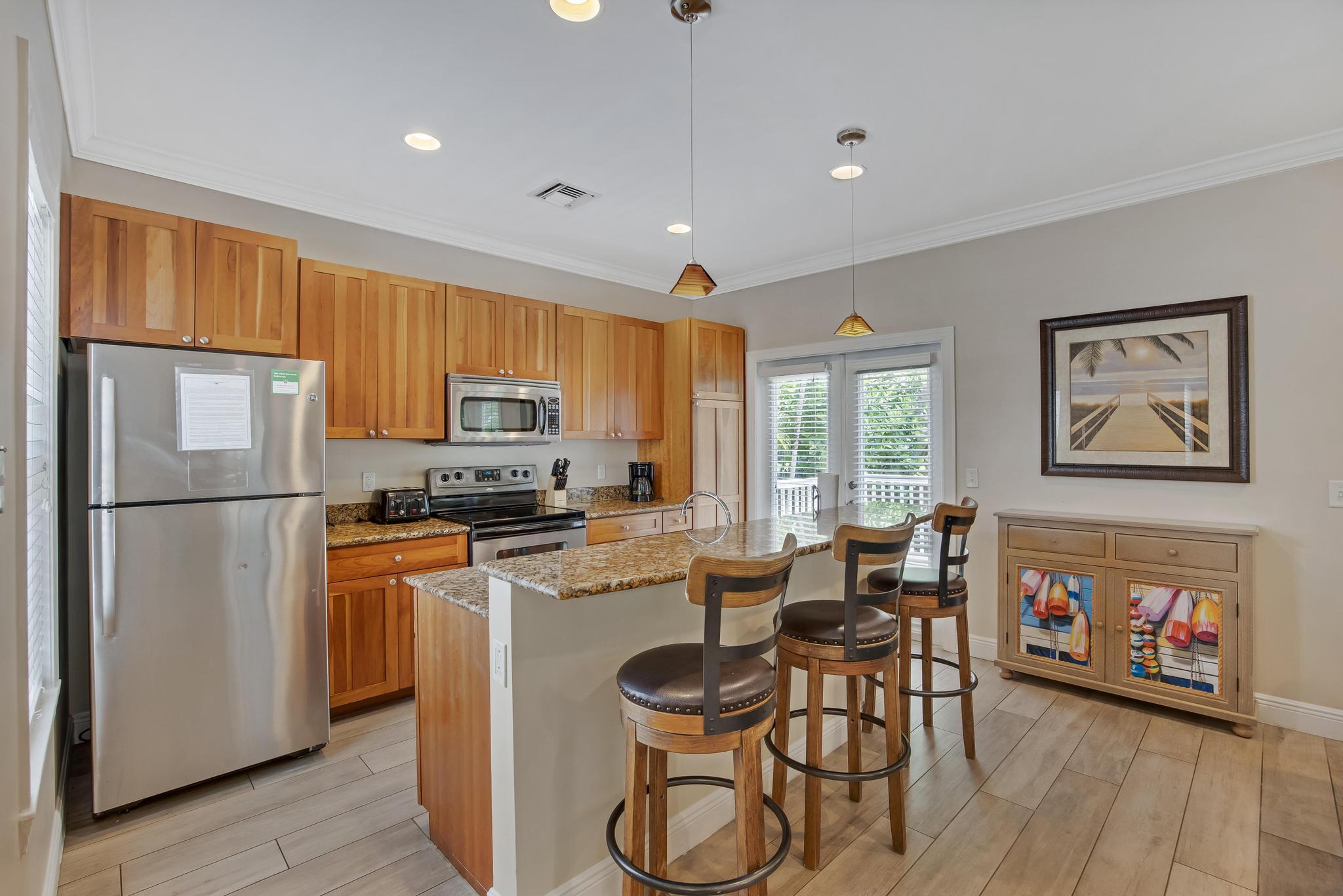 7204 Simran Lane Marathon, FL 33050 - Photo 5 of 47 a kitchen with stainless steel appliances granite countertop a refrigerator a stove a sink a dining table and chairs with wooden floor