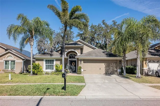 a front view of a house with a garden and palm trees