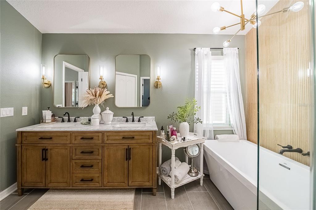 2524 Siena Way Valrico, FL 33596 - Photo 24 of 38 a bathroom with a double vanity sink a large mirror and a bathtub