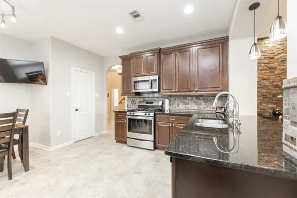 a kitchen with stainless steel appliances granite countertop a sink refrigerator and cabinets